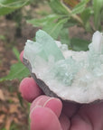 Video shows a piece of green apophyllite, palm sized in size.