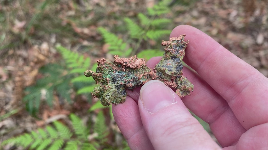 Video shows a native copper specimen. Green and copper in colour and freeform in shape. 