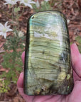 Video shows polished Labradorite free form crystal. The crystal has a lot of  colour flash in bluish, yellowish and greenish colours. 