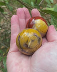 Video of two different Mookaite spheres. one is a deep red colour within and yellow inclusions, the other is a mustard yellow colour with slight burgundy banding. 