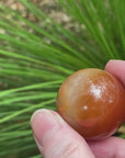 Video shows a carnelian sphere, burnt orange in colour. 