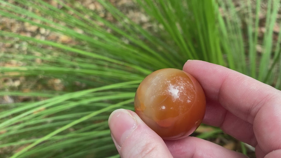 Video shows a carnelian sphere, burnt orange in colour. 