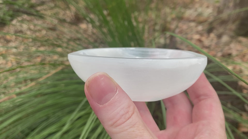 Video shows a white selenite round bowl shape. It has a shiny lustre and is 10cm in diameter