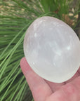 the video shows an oval shaped, polished selenite palm stone, white in colour with a shiny lustre. 