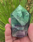 Video shows a polished fluorite generator, purple, green and clear in colour. 