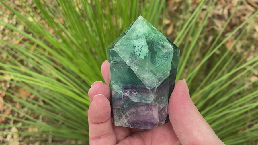 Video shows a polished fluorite generator, purple, green and clear in colour. 