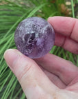 video shows an amethyst sphere, purple in colour and including lots of inclusions. 