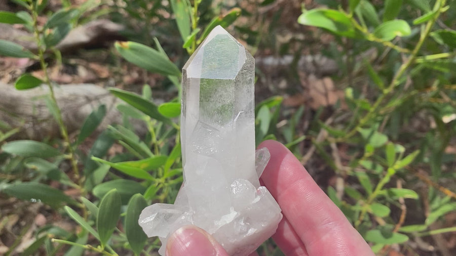 Video shows a clear quartz natural cluster with a large main point. It measures H 10cm W 6cm D 4cm 