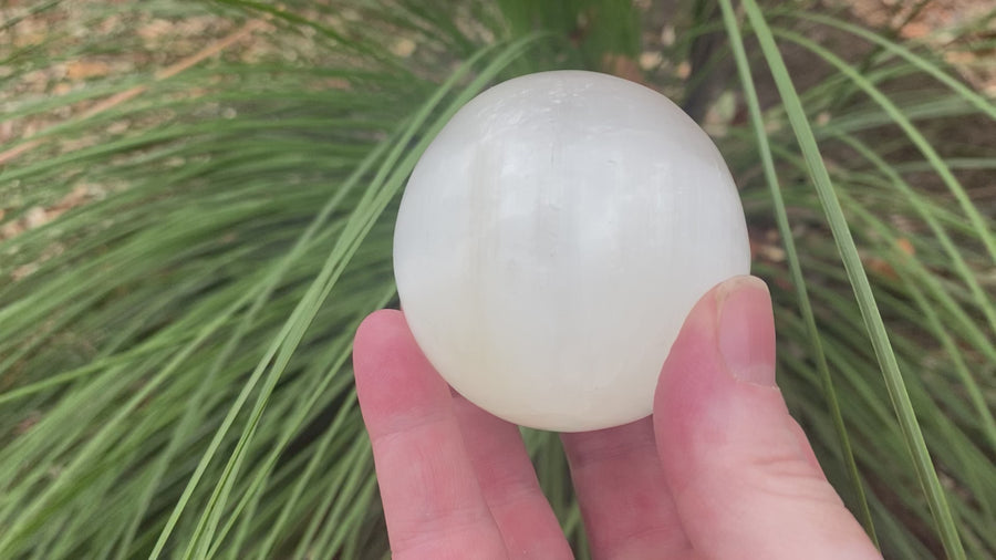 Video shows a white selenite polished sphere. white in colour with a shiny lustre. 