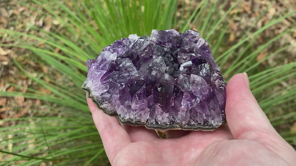 Video shows an amethyst cluster, deep purple in colour with long crystals and very little matrix. 