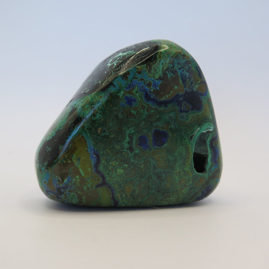 Image shows a polished piece of azurite and malachite with deep hues of blue and green in a marbled pattern. 