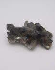 Image shows a smokey quartz cluster with very little matrix. It is blackish to dark grey in colour with translucent crystals. 